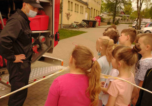 Strażak prezentuje wyposażenie wozu bojowego.
